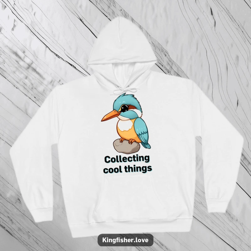 Funny hoodie showing a kingfisher holding a shiny pebble in its beak, head tilted curiously, perfect for cozy, inquisitive vibes.